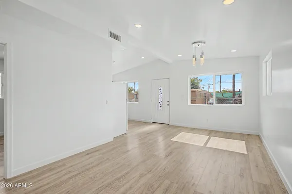 an empty room with wooden floor and windows
