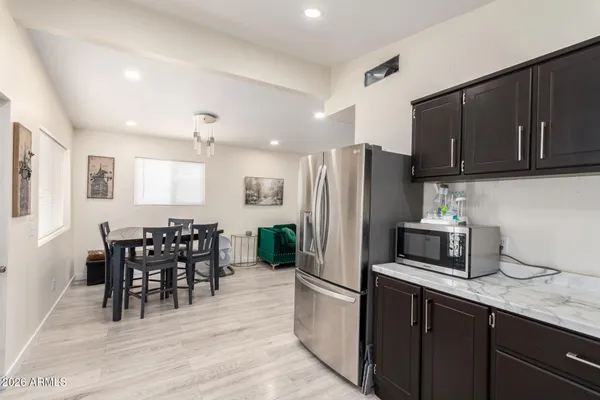 a kitchen with stainless steel appliances granite countertop a refrigerator a stove a sink a dining table and chairs