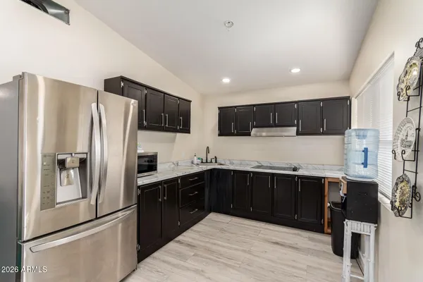 a kitchen with stainless steel appliances granite countertop a refrigerator a sink a stove a microwave and wooden cabinets
