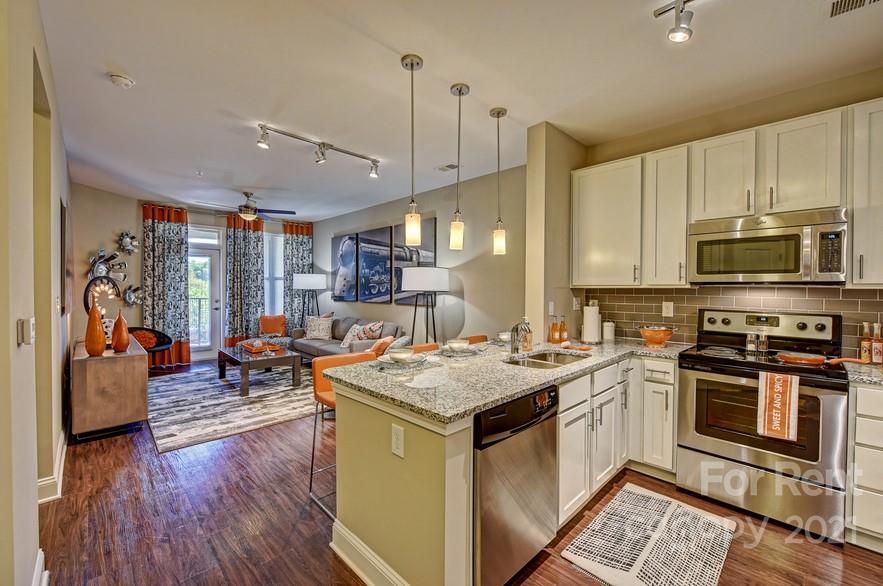 703 Rollerton Road Charlotte, NC 28205 - Photo 13 of 27 a kitchen with a stove a sink dishwasher a refrigerator and a dining table with wooden floor