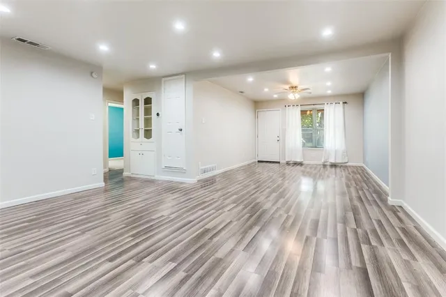 an empty room with wooden floor and windows