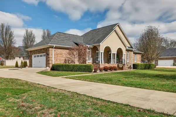 a view of a white house next to a yard and large trees