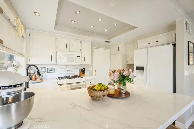 a kitchen with stainless steel appliances granite countertop a refrigerator a stove and white cabinets