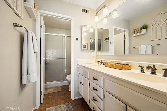 a spacious bathroom with a double vanity sink toilet mirror and shower