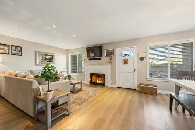 a living room with furniture a fireplace wooden floor and a large window