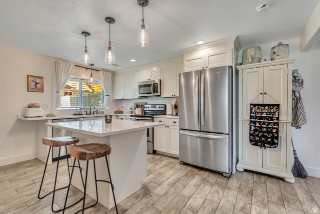 1071 Jamie-Matt Circle Layton, UT 84041 - Photo 4 of 28 Kitchen with stainless steel appliances, a kitchen breakfast bar, wood tiled floors, and white cabinets