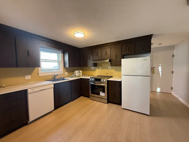 a kitchen with stainless steel appliances granite countertop a refrigerator a sink dishwasher a stove top oven a refrigerator and white cabinets