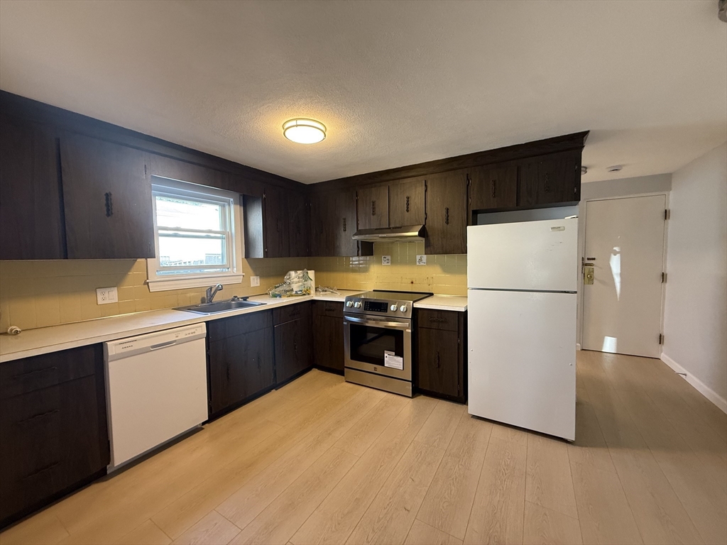 a kitchen with stainless steel appliances granite countertop a refrigerator a sink dishwasher a stove top oven a refrigerator and white cabinets