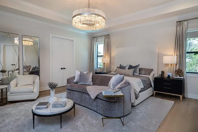 a spacious bedroom with a bed a couch and a chandelier