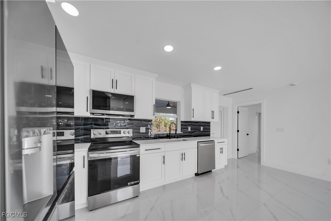 855 Foxtail Street East Lehigh Acres, FL 33974 - Photo 3 of 23 a kitchen with stainless steel appliances a stove sink microwave and cabinets