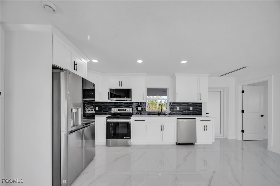 855 Foxtail Street East Lehigh Acres, FL 33974 - Photo 5 of 23 a kitchen with stainless steel appliances granite countertop a stove top oven a sink and a refrigerator