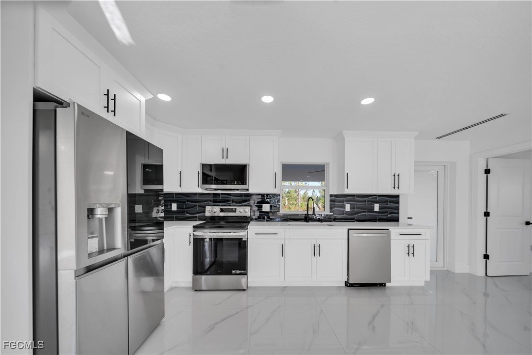 855 Foxtail Street East Lehigh Acres, FL 33974 - Photo 6 of 23 a kitchen with stainless steel appliances granite countertop a stove top oven a sink and a refrigerator