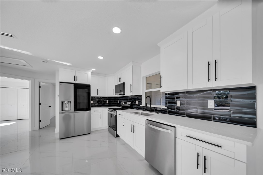 855 Foxtail Street East Lehigh Acres, FL 33974 - Photo 7 of 23 a kitchen with stainless steel appliances a refrigerator sink and cabinets
