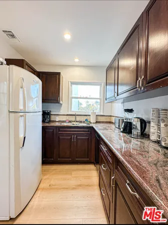 a kitchen with granite countertop stainless steel appliances a refrigerator a sink and a counter