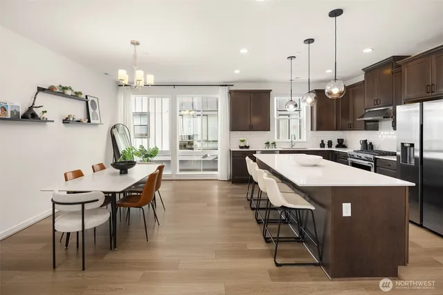 a kitchen with stainless steel appliances kitchen island granite countertop a table chairs sink and microwave