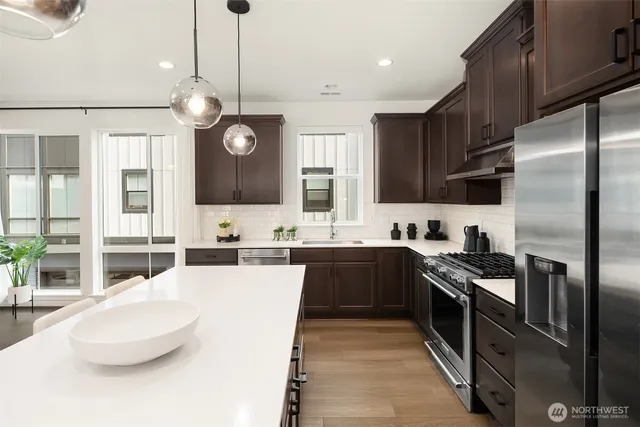 a large kitchen with stainless steel appliances granite countertop a sink a stove and a refrigerator