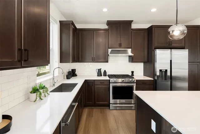 a kitchen with stainless steel appliances granite countertop a sink a stove and a wooden floors
