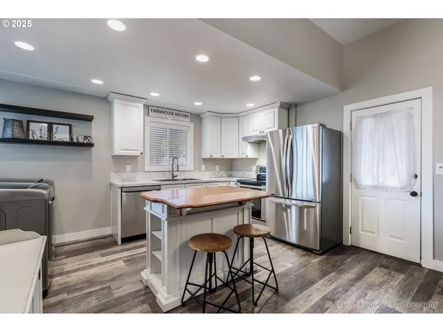 a kitchen with stainless steel appliances granite countertop a refrigerator a sink a stove a dining table and chairs