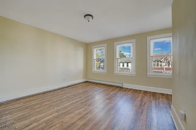a view of an empty room with window and wooden floor
