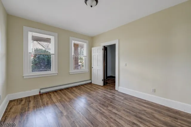 a view of an empty room with window and wooden floor