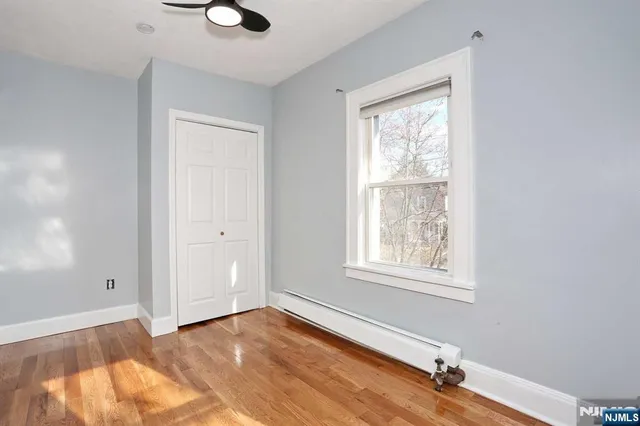 a view of an empty room with a window and wooden floor
