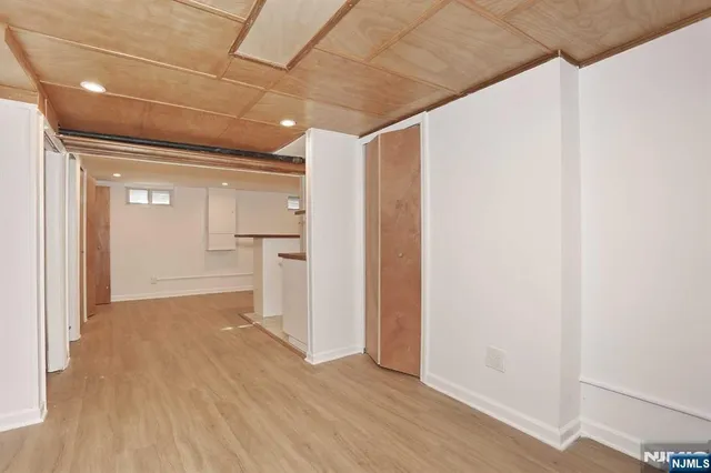a view of a hallway with wooden floor and a refrigerator