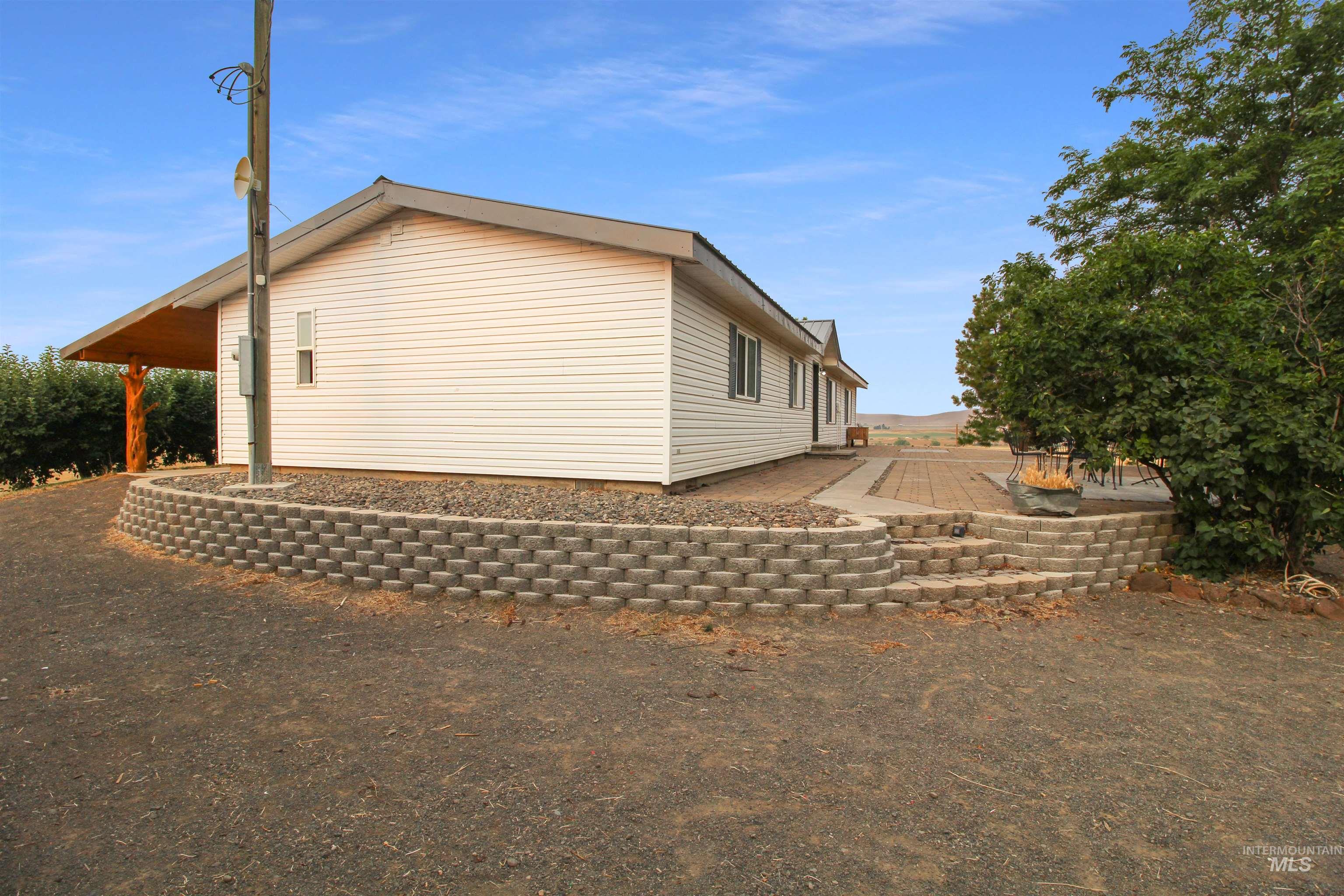 2469 Hague Road Midvale, ID 83645 - Photo 45 of 50 Exterior showcasing white siding, a covered patio with exposed wood beams, and a tiered block retaining wall