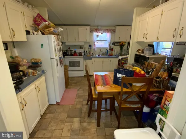 a kitchen with stainless steel appliances kitchen island granite countertop a refrigerator a stove a sink dishwasher and white cabinets with wooden floor