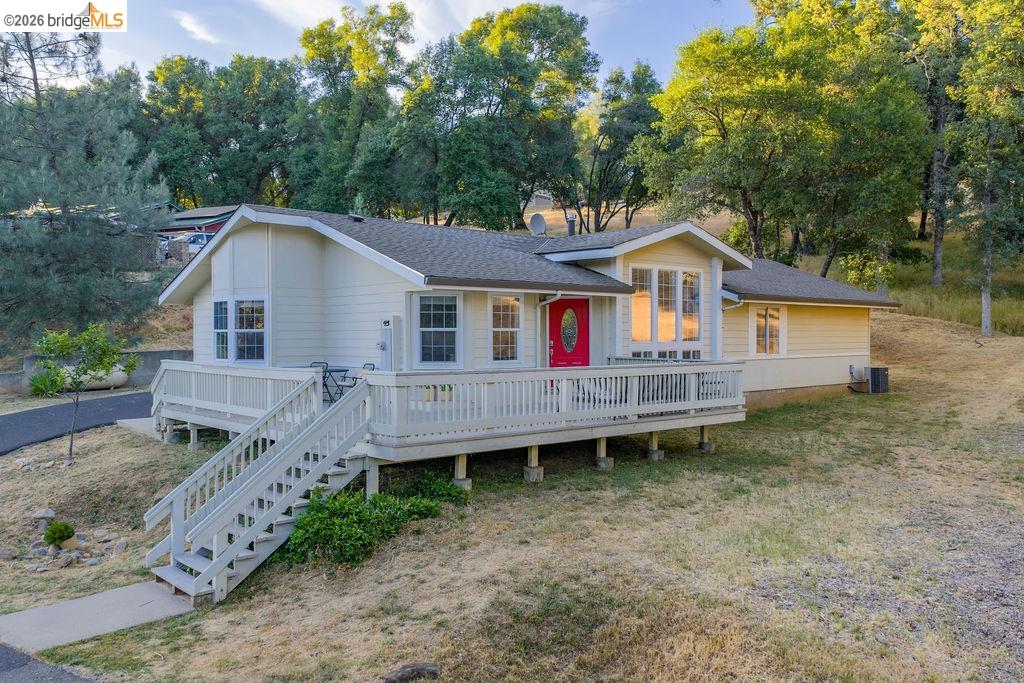 20828 Ferretti Road Groveland, CA 95321 - Photo 1 of 60 View of front of house featuring a shingled roof, a deck, a chimney, and view of wooded area