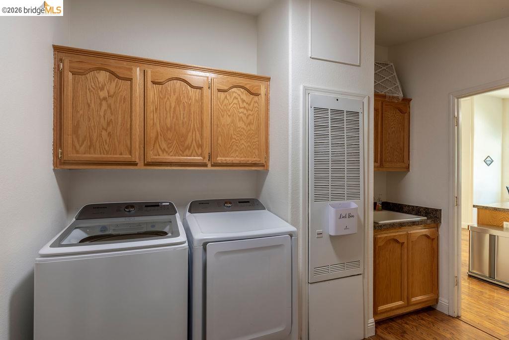 20828 Ferretti Road Groveland, CA 95321 - Photo 16 of 60 Laundry room featuring a heating unit, cabinet space, light wood finished floors, and washing machine and dryer