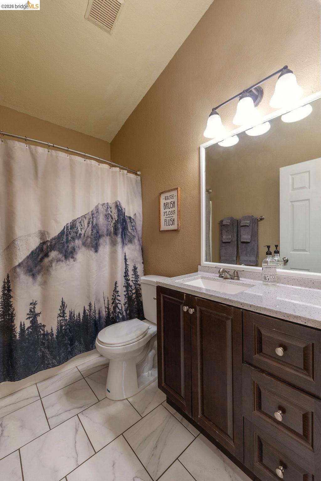 20828 Ferretti Road Groveland, CA 95321 - Photo 18 of 60 Bathroom with vanity, a shower with curtain, light marble finish floors, vaulted ceiling, and a textured wall