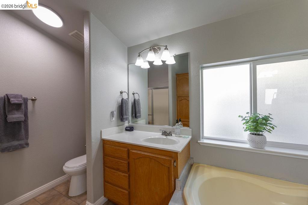 20828 Ferretti Road Groveland, CA 95321 - Photo 21 of 60 Bathroom with vanity, a garden tub, a shower stall, a textured wall, and light tile patterned floors