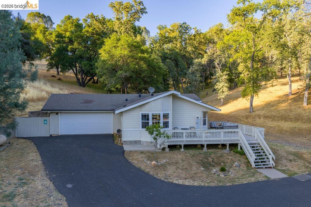 20828 Ferretti Road Groveland, CA 95321 - Photo 38 of 60 View of front facade with a wooden deck, driveway, a garage, and view of scattered trees