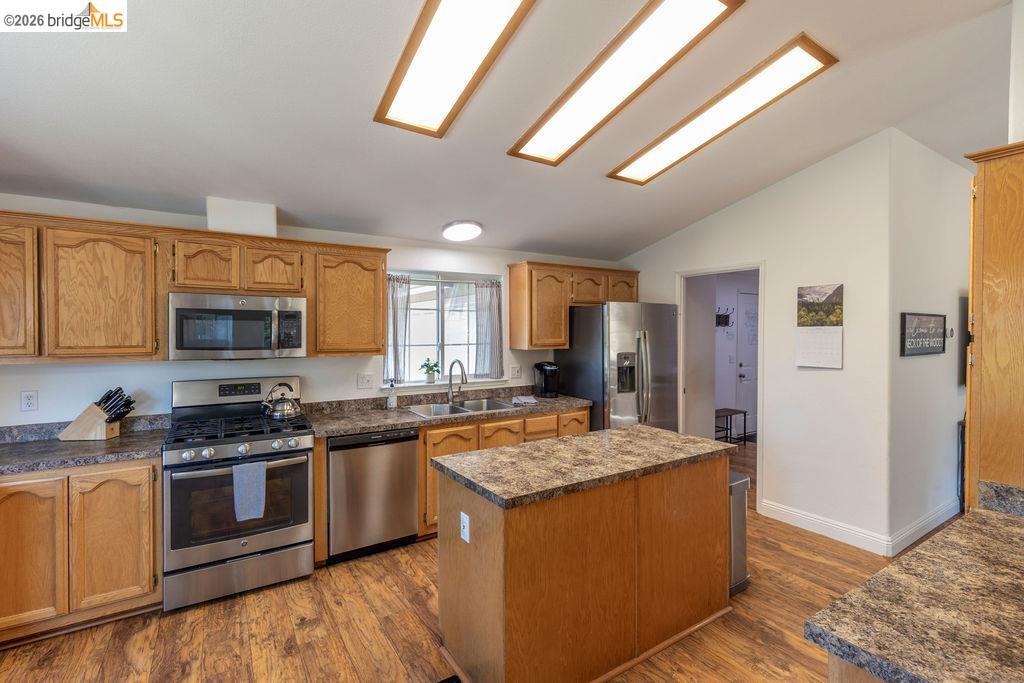 20828 Ferretti Road Groveland, CA 95321 - Photo 7 of 60 Kitchen with stainless steel appliances, dark countertops, a kitchen island, dark wood-style floors, and vaulted ceiling