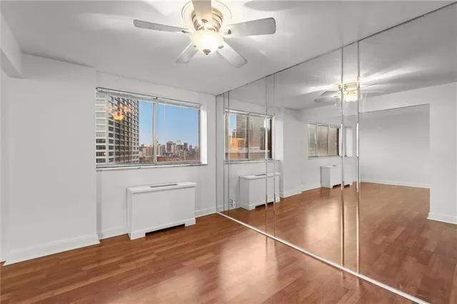 a room with a chandelier fan and kitchen view