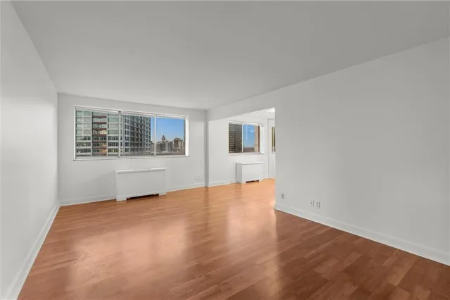 a view of an empty room with a window and wooden floor