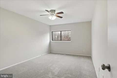 an empty room with a window and a fan