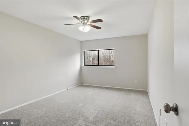 an empty room with a window and a fan