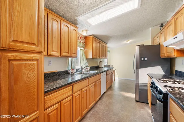 a kitchen with stainless steel appliances granite countertop a stove a sink and a refrigerator