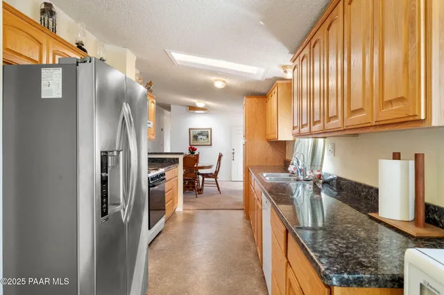 a kitchen with stainless steel appliances granite countertop a refrigerator a oven a sink with island and chairs
