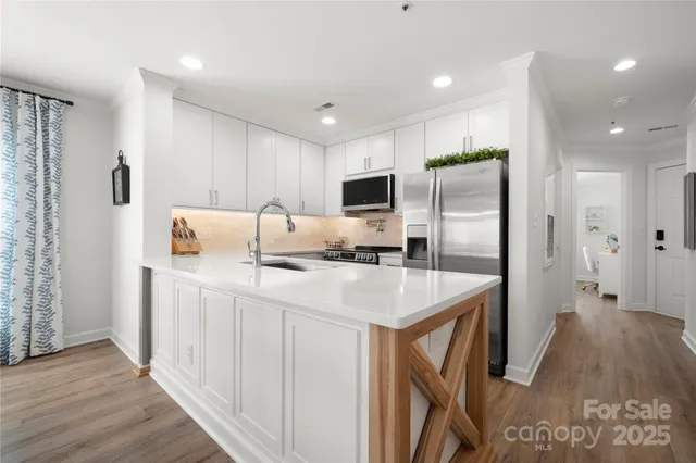 a kitchen with stainless steel appliances a refrigerator a sink and white cabinets