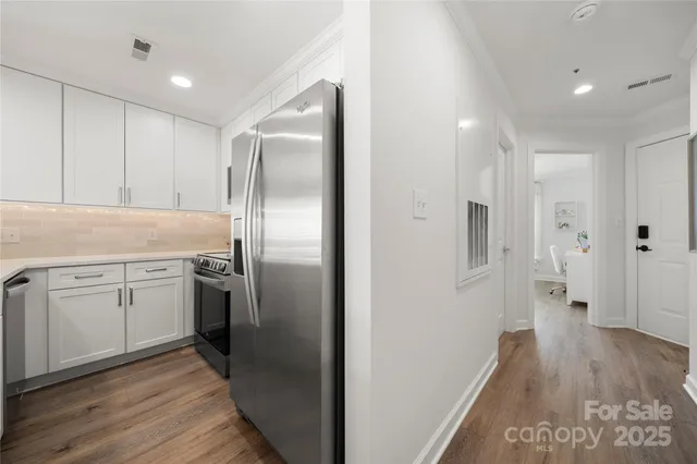 a kitchen with white cabinets appliances and potted plant