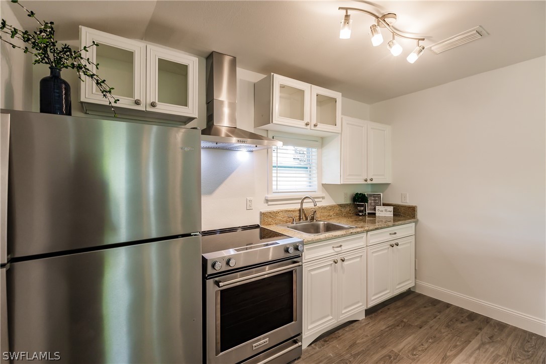 2502 Lake Trafford Road Immokalee, FL 34142 - Photo 9 of 15 a kitchen with stainless steel appliances granite countertop a refrigerator a sink dishwasher a stove and a refrigerator with wooden floor