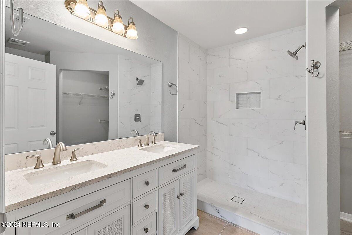 a bathroom with a shower sink double vanity and a mirror