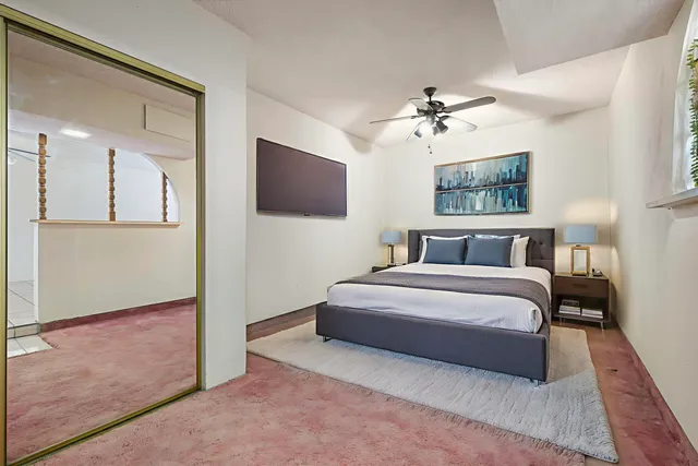 a spacious bedroom with a bed and a flat screen tv