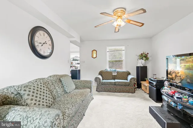 a living room with furniture a clock on wall and a large window