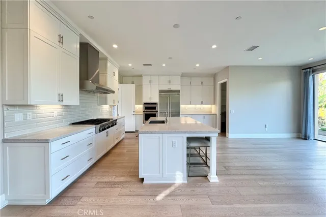 a large kitchen with stainless steel appliances kitchen island granite countertop a large counter top and a stove top oven