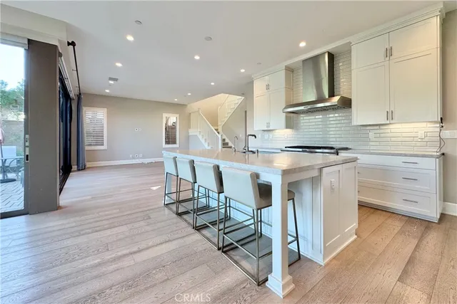 a kitchen with stainless steel appliances kitchen island granite countertop a stove a refrigerator and white cabinets with wooden floor