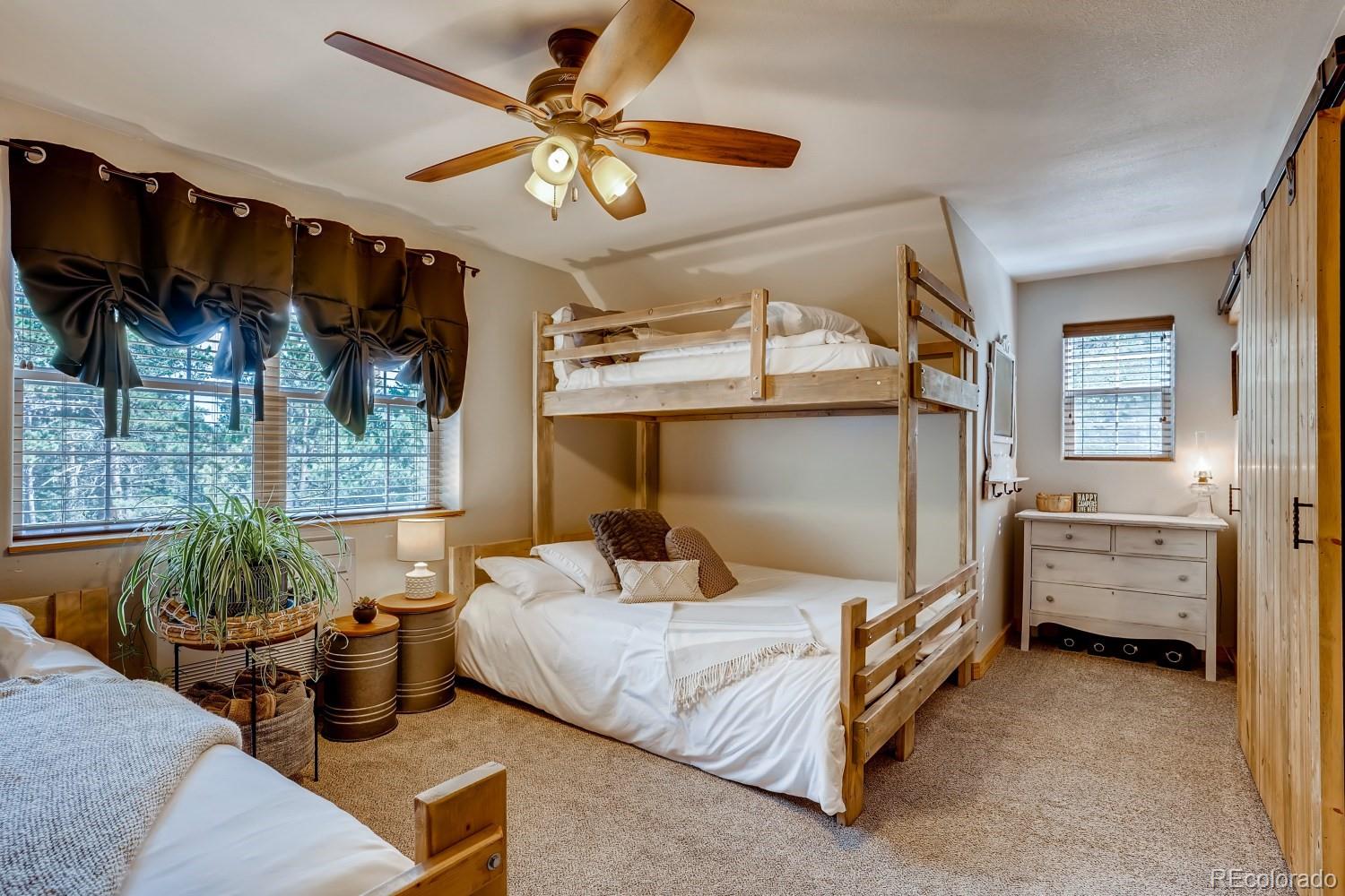 13380 South Foxton Road Conifer, CO 80433 - Photo 27 of 40 a bedroom with a bed a ceiling fan and a dresser
