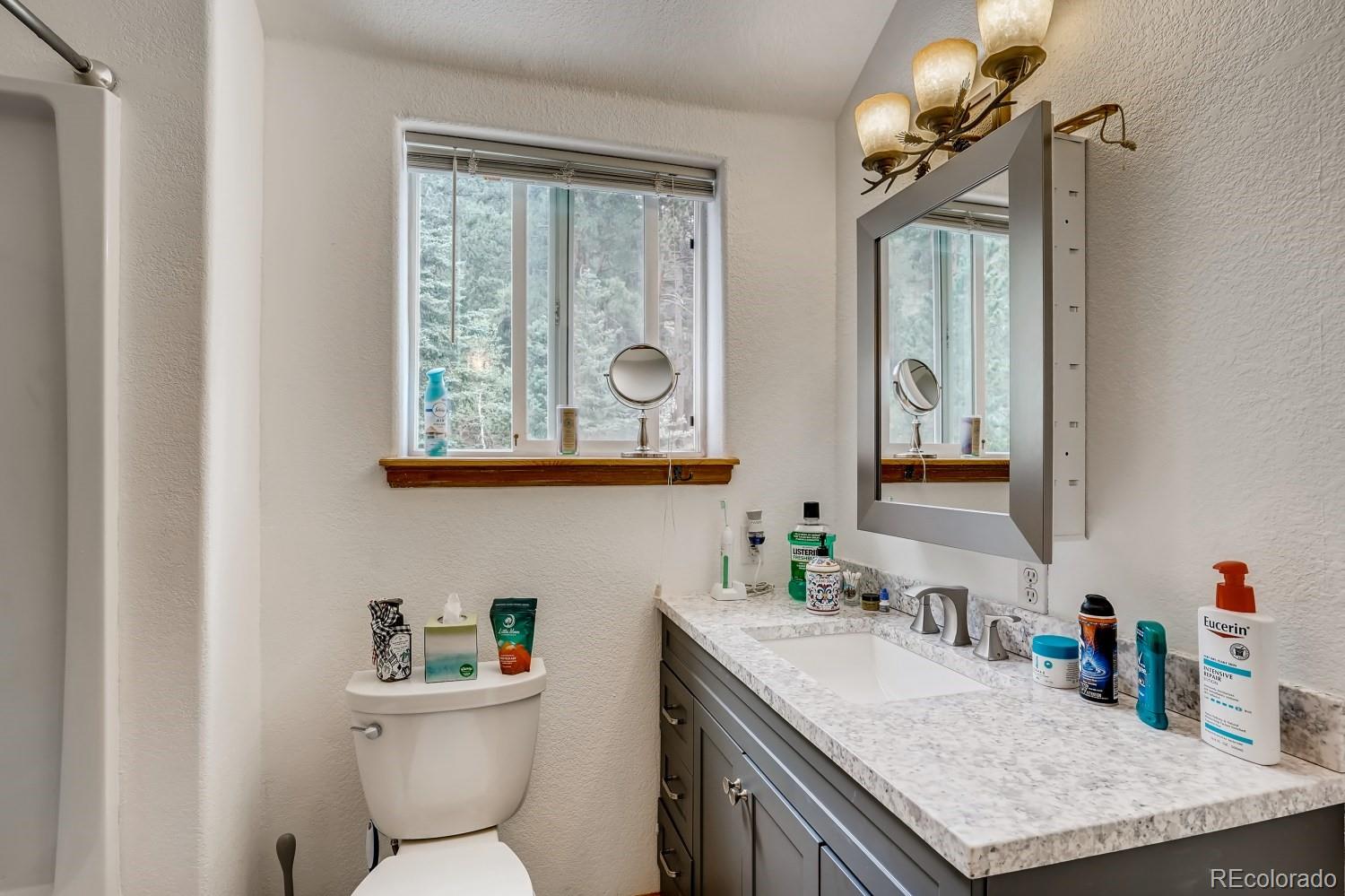 13380 South Foxton Road Conifer, CO 80433 - Photo 36 of 40 a bathroom with a granite countertop toilet sink and mirror